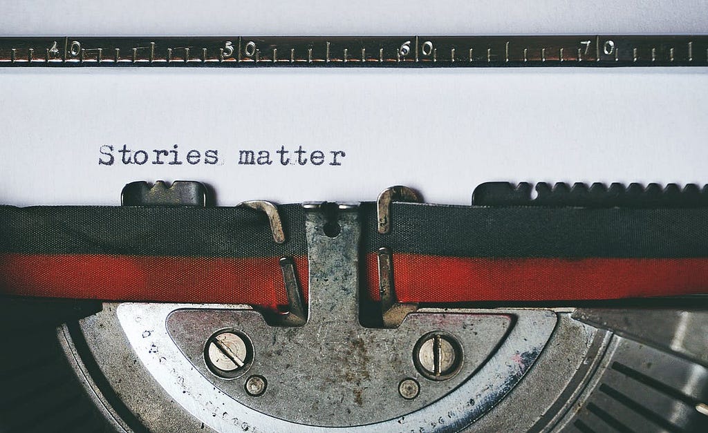 Close up of the paper in a type writer with the phrase “stories matter” typed out.