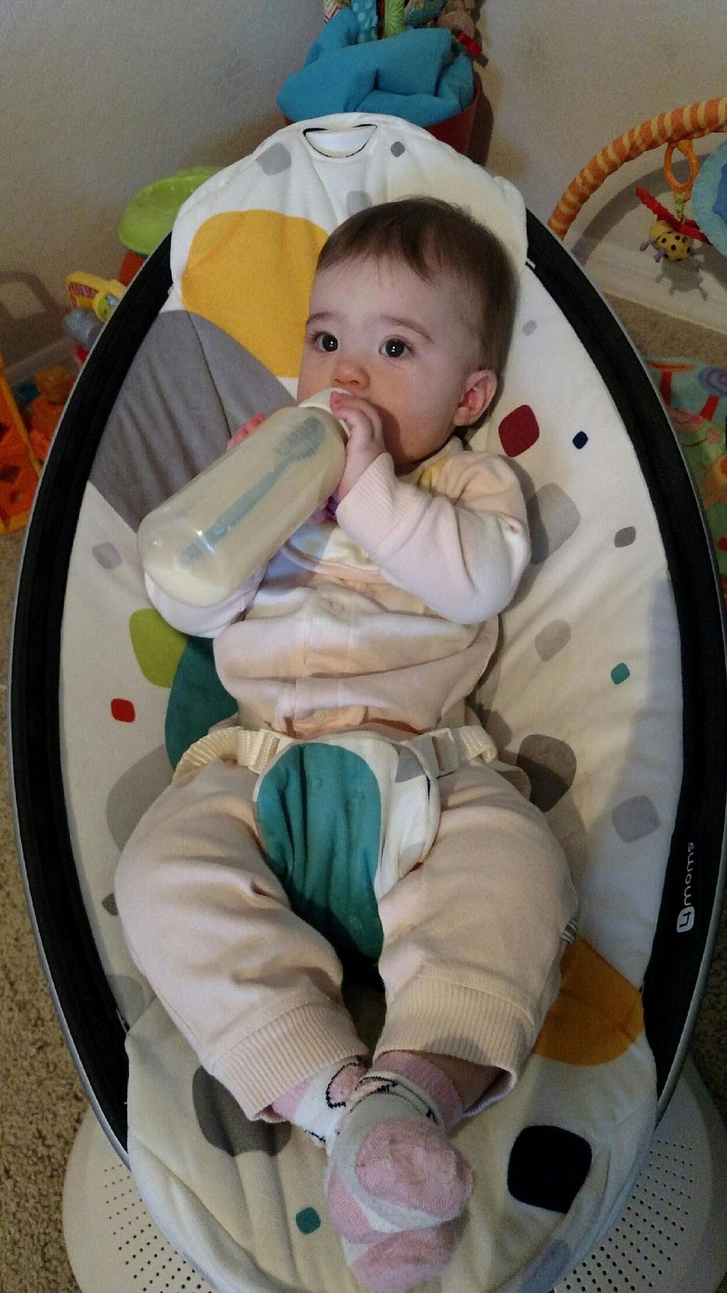 Baby girl holding her own bottle.