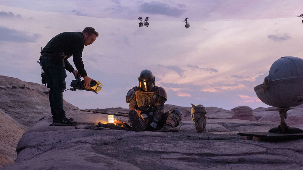 On set of The Mandalorian, showing the protagonist, the child and film crew