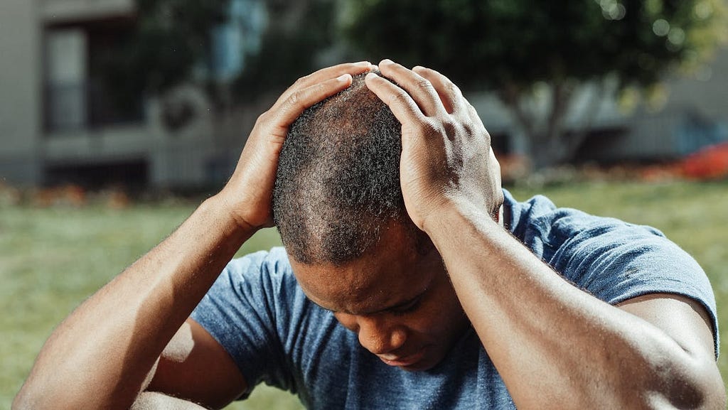 A man clutching his head, perhaps due to stress or overwhleming emotions.