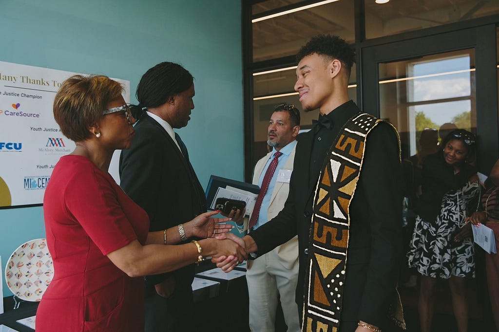 Cayden Brown handshake with Senator Sylvia Santana as they receive advocacy awards from the Michigan Center for Youth Justice