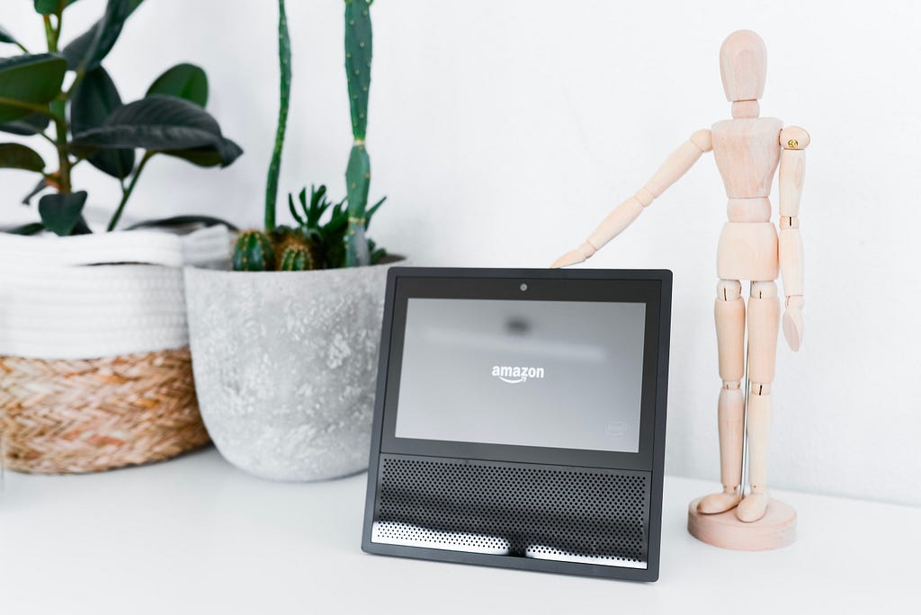 Amazon echo screen on a desk next to plants and a mannequin