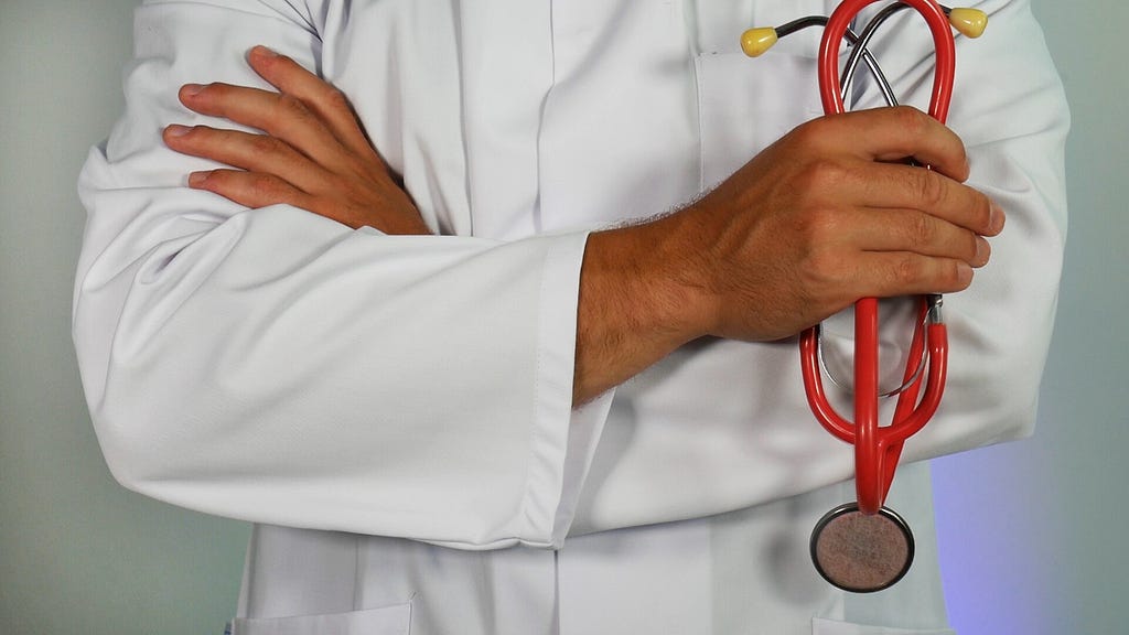 A Doctor Stands Cross-Armed Holding his Stethoscope.