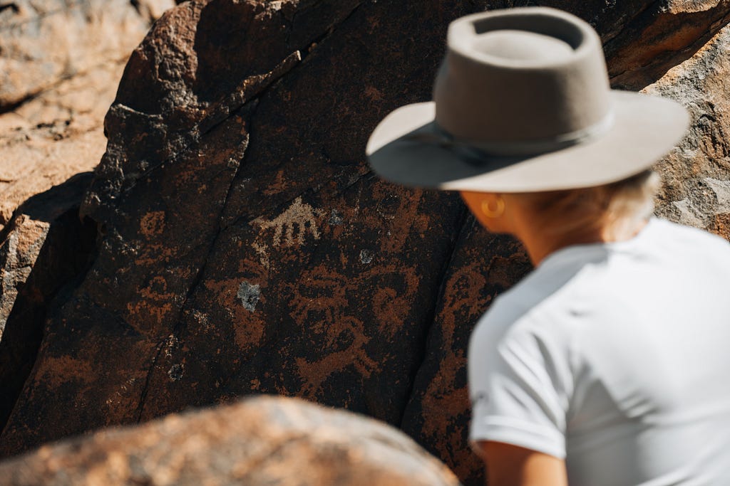 In the NEOM region, several rock carvings depict camels in various sizes and styles, and at varying levels of detail. Here we see dromedary camel observed by a woman with a hat.