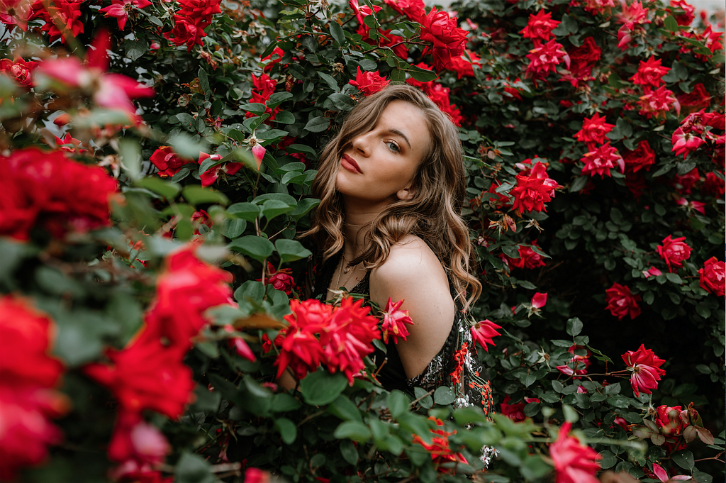 Alex Lilly poses in a garden of roses.