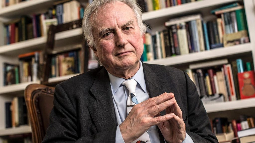 Richard Dawkins sitting on a chair with a bookshelf in the background.