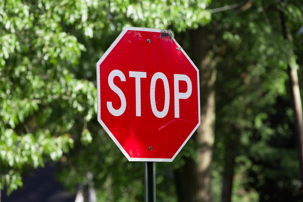 Stop sign in the foreground, blurred trees in the background.