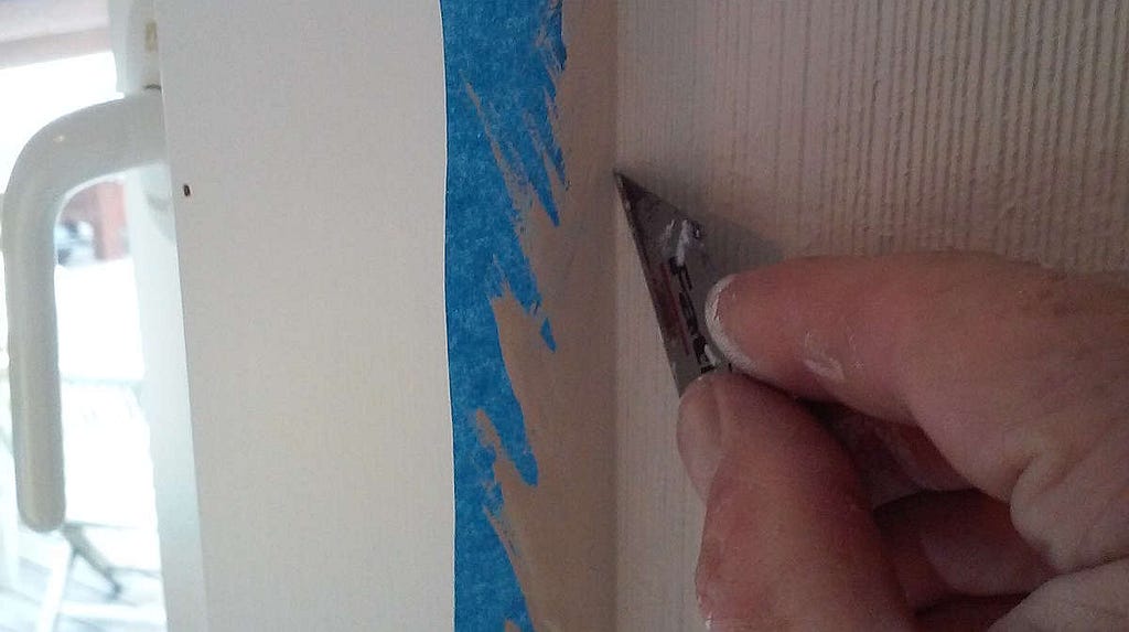 Cutting heavy paint on blue masking tape to free the tape