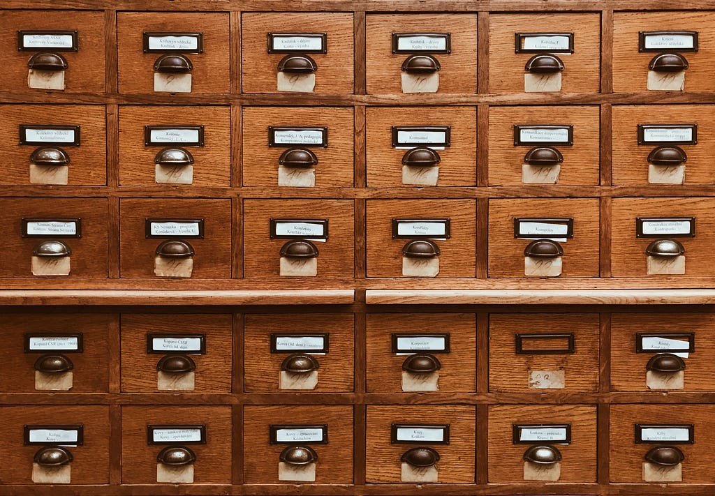 an ancient file cabinet with many labeled drawers.
