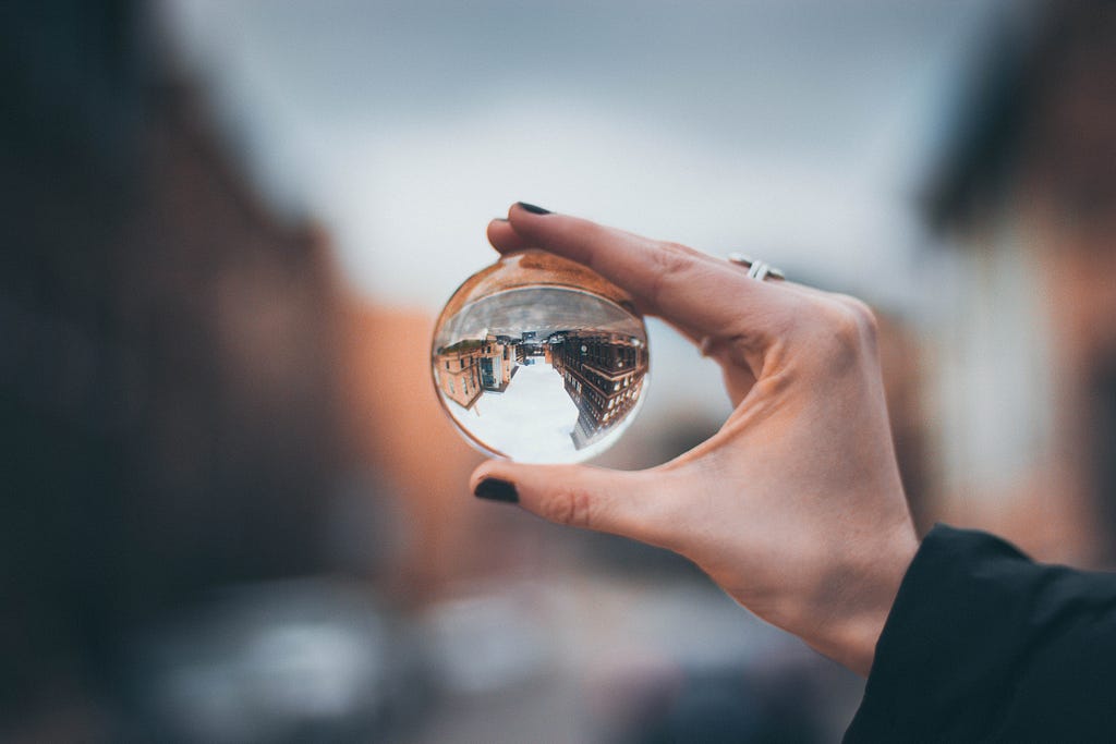 A woman’s hand holding a glass sphere that turns the view upside down
