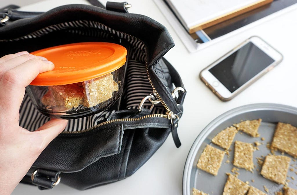 ginger turmeric bone broth protein bites in a container being placed in a purse