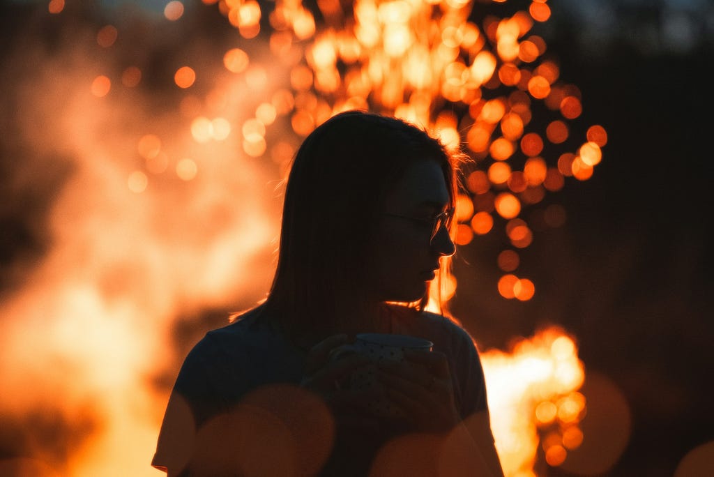 Woman in front of a fire with head turned to side, as profile