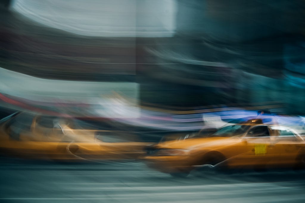 Blurred photos of taxis going past in a street.