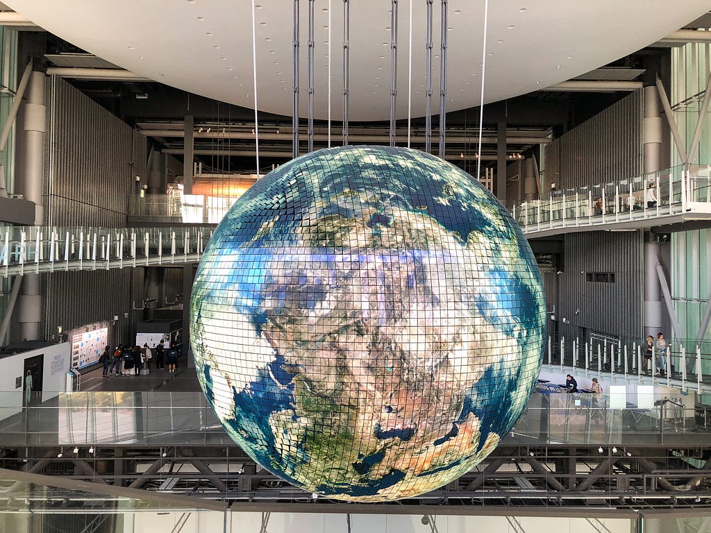 A globe hangs in an exhibition space.