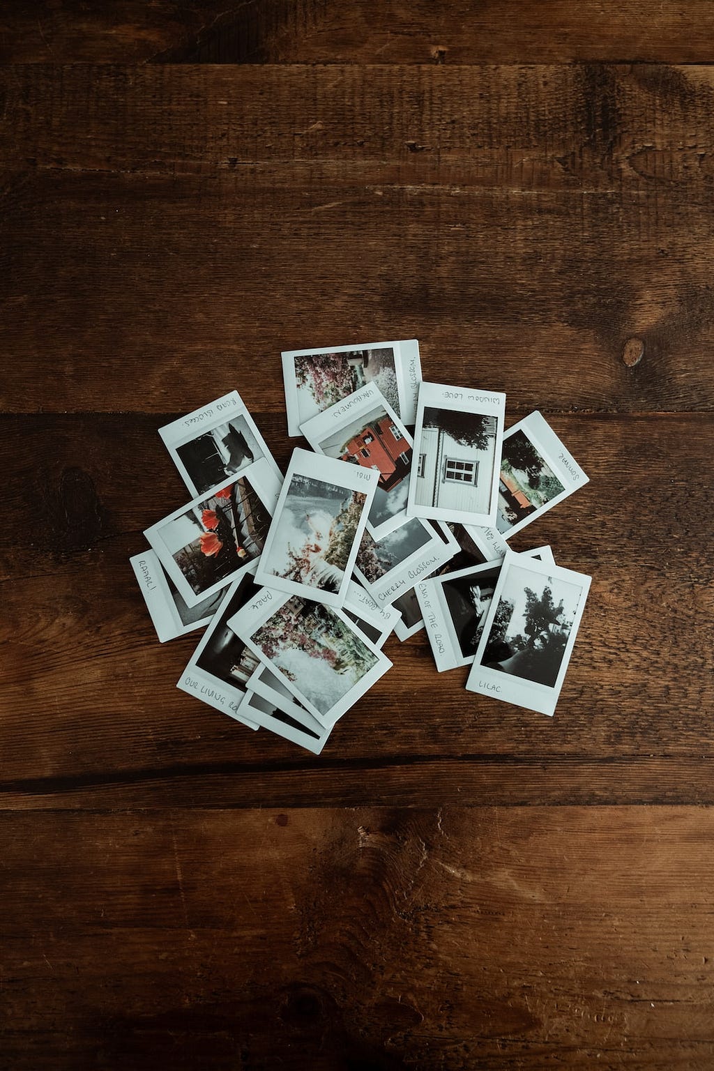 A wooden tabletop with a pile of Instax instant photos.