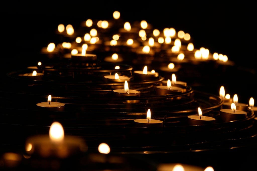 A bunch of small lit candles luminating a dark room.