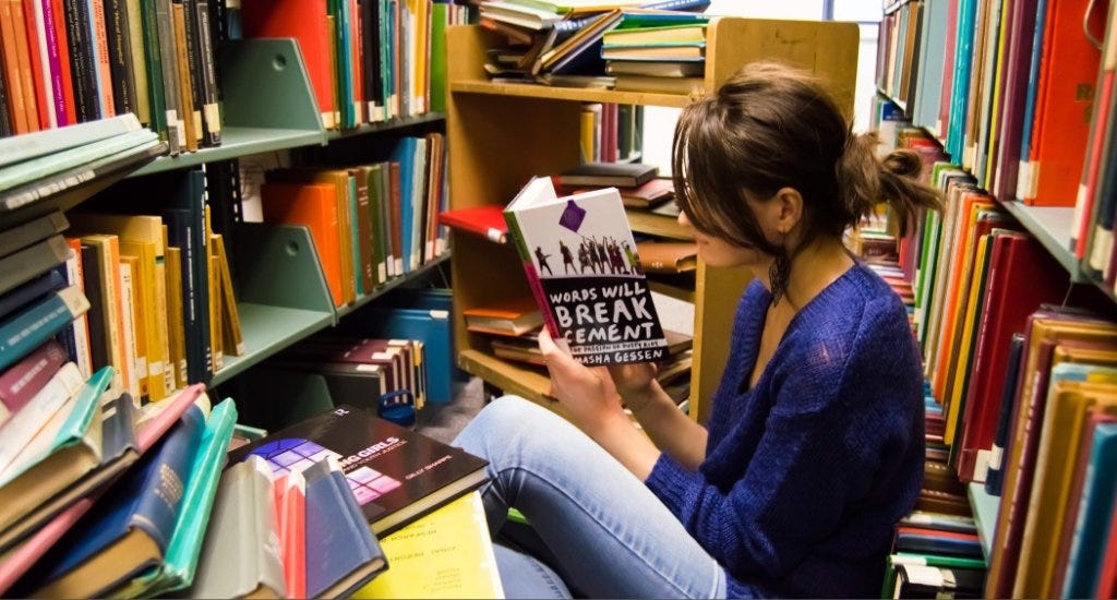 Teen reading a book while surrounded by other books