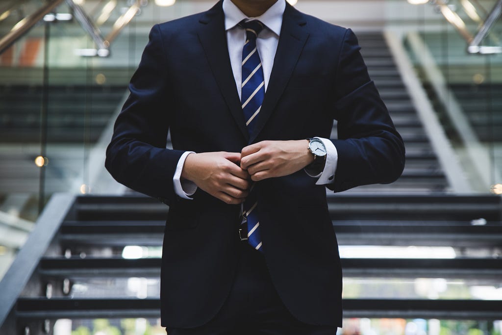 male person wearing blue coat and tie symbolizing success