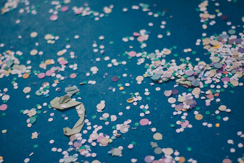 Fotografia de confetes coloridos em um chão escuro.