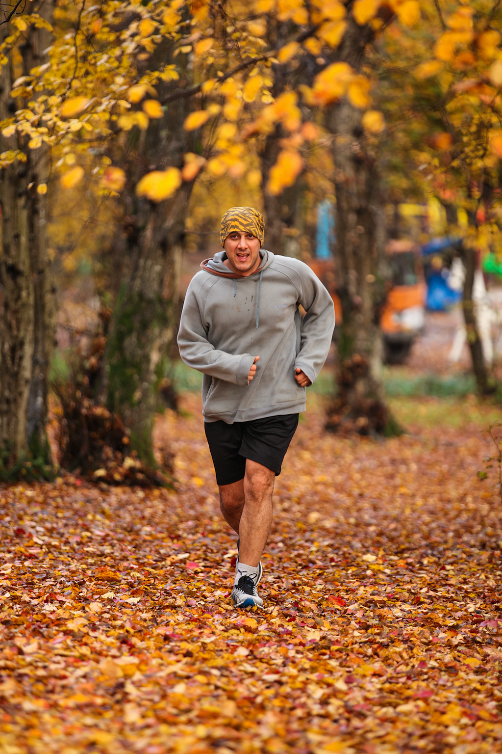 Man running on a path surrounded by trees and fall leaves