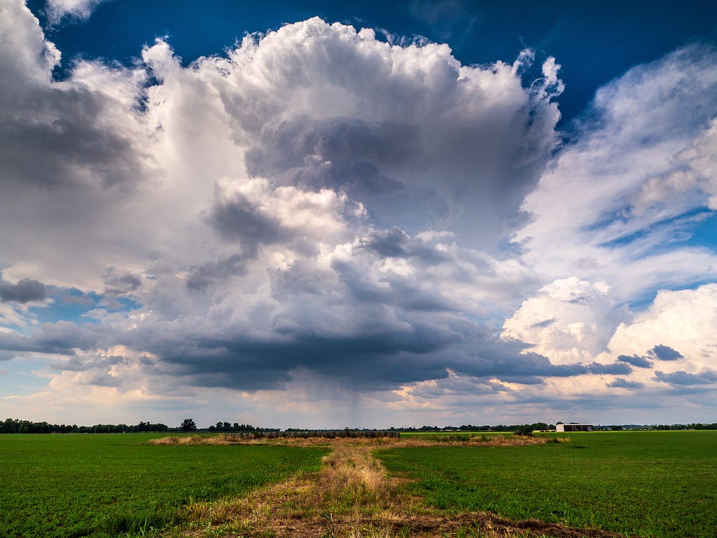 A big cumulonimbus cloud above a grassy field