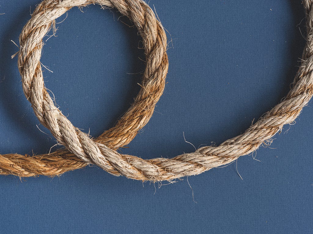 A hemp rope lightly looped back against a blue background