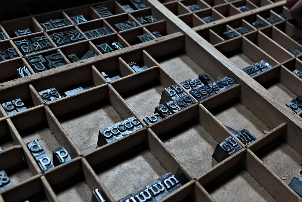 letters from a printing press organized by letter in a set of wooden compartments;