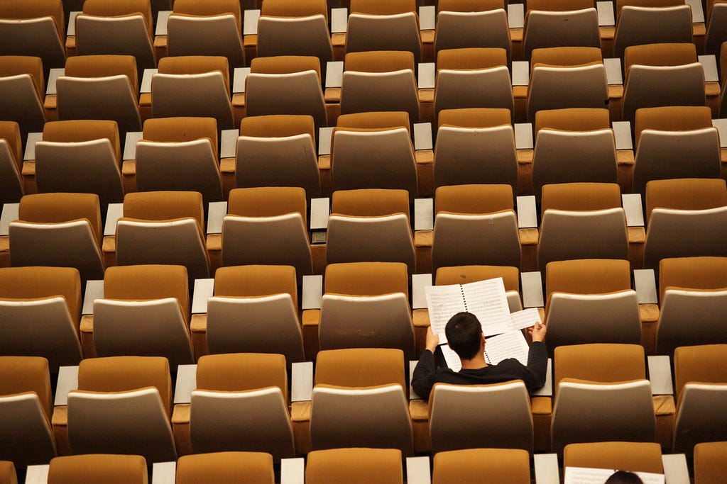 One person sitting with a book in an auditorium.