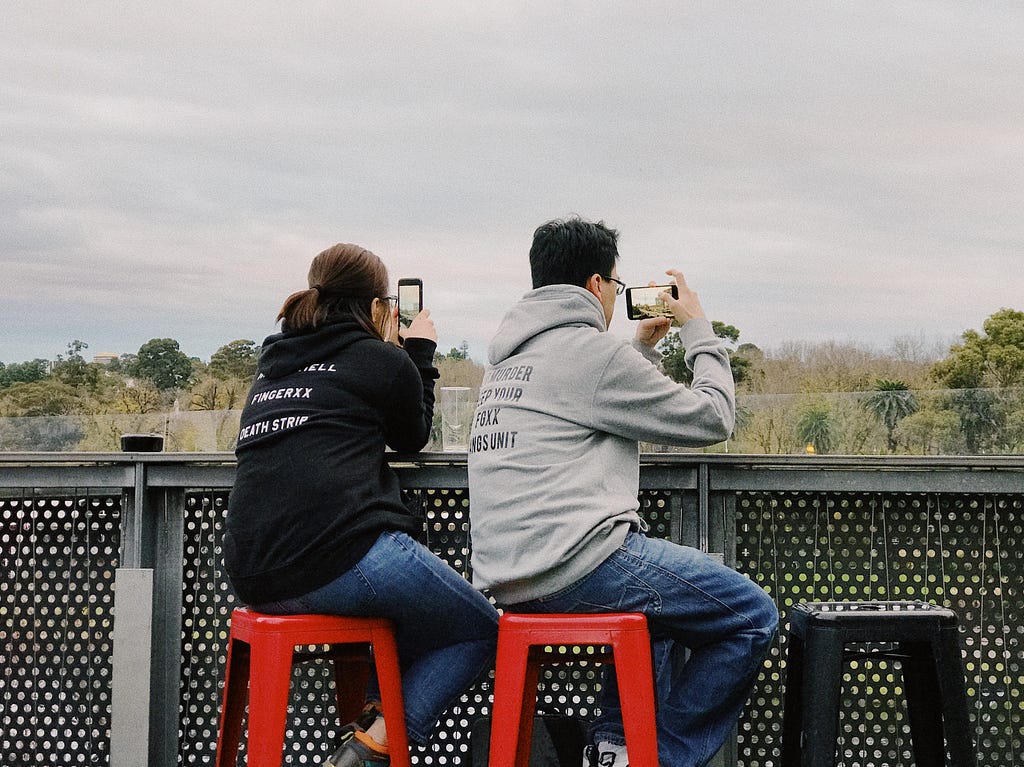 Two people using smartphones. One person is using it in portrait position and another in landscape position.