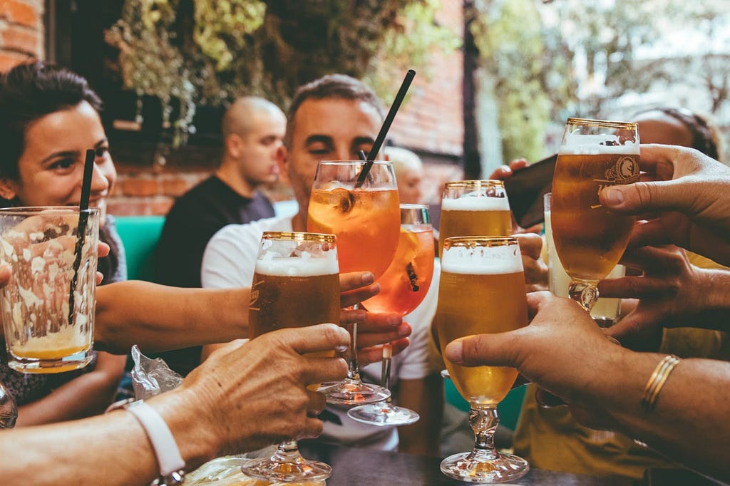 A group of people raising their drink glasses around a table.