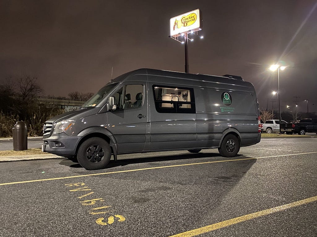 The camper van parked in a Cracker Barrel parking lot.