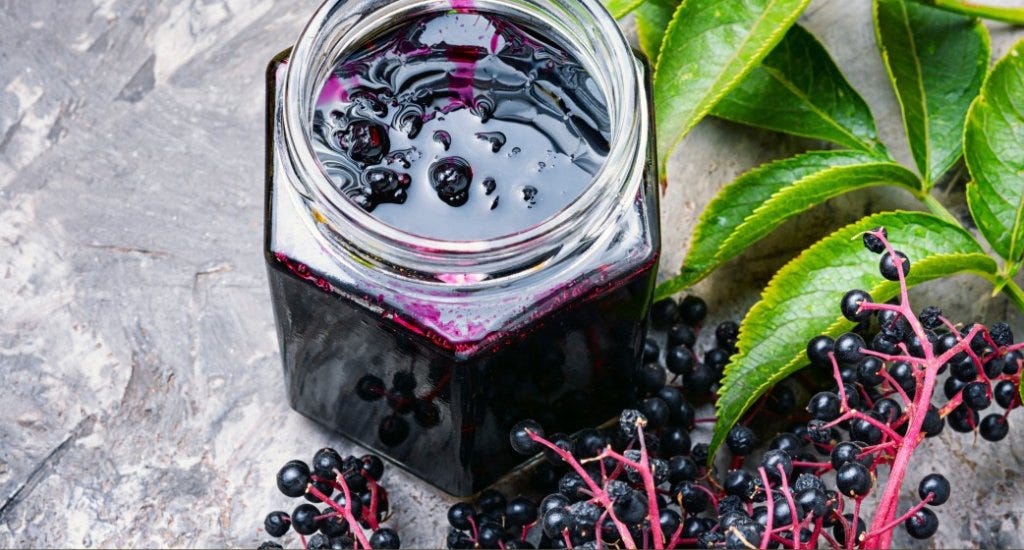 Jar of elderberry juice next to some elderberries