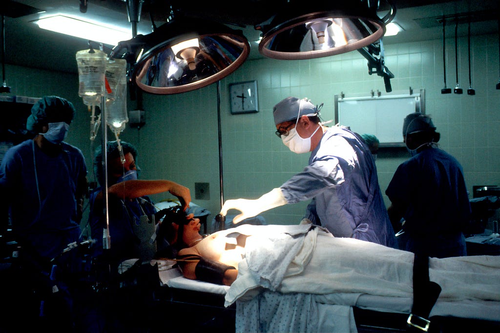 Patient on gurney in operating room with doctors looking down