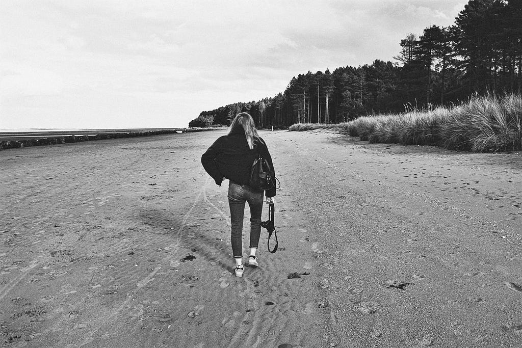 Woman walking on a sandy beach.