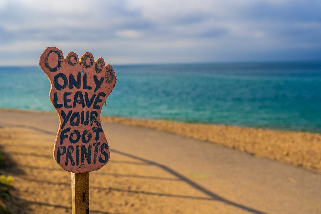 A sign by the beach saying only leave your foot prints.