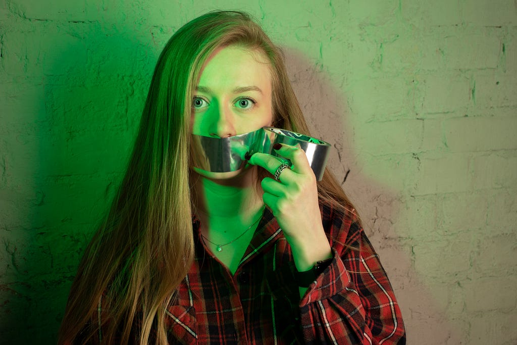 girl with duct tape over her mouth to signify silence