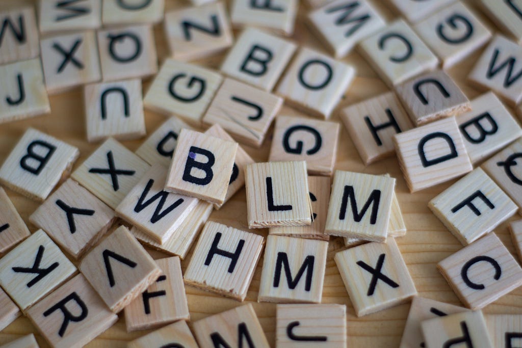 Wooden Scrabble-letter tiles scattered across a wooden table-top