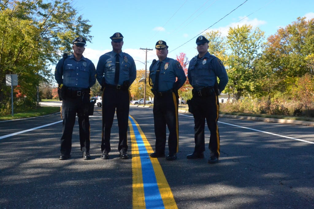 From left to right, SFC. Jim D’Averso, Lt. Arthur Waterman, Chief Richard Meder and Police Officer Greg Blash stand above the newly painted blue line on Union Street, meant to symbolize the town’s support of police.