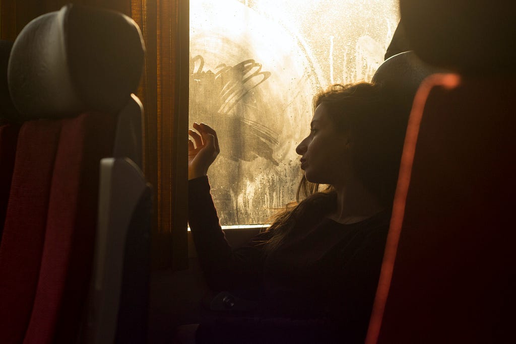Girl sitting on a train looking out the window