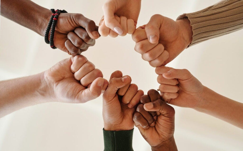 Six fits of diverse races joined together around a circle in solidarity