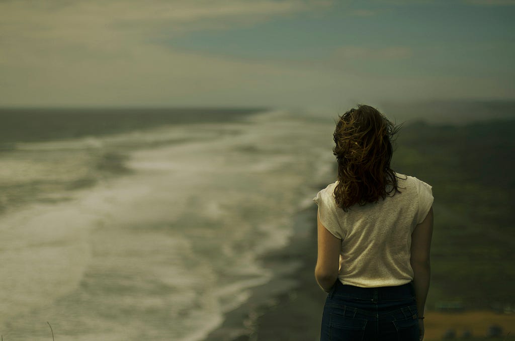 woman staring out into the sea on a cloudy day