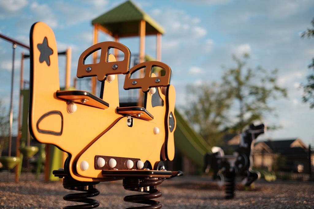 A playground with a spring swing in the foreground