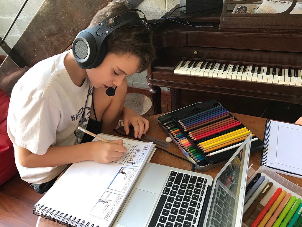 Sebastian focused on writing a comic for school, using headphones to concentrate.