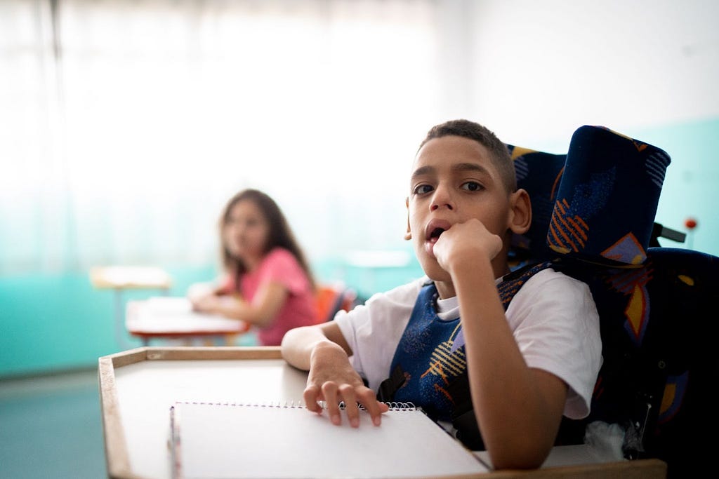 Young boy in wheelchair with a neuromuscular condition, seated in classroom — Invitae genetic testing blog