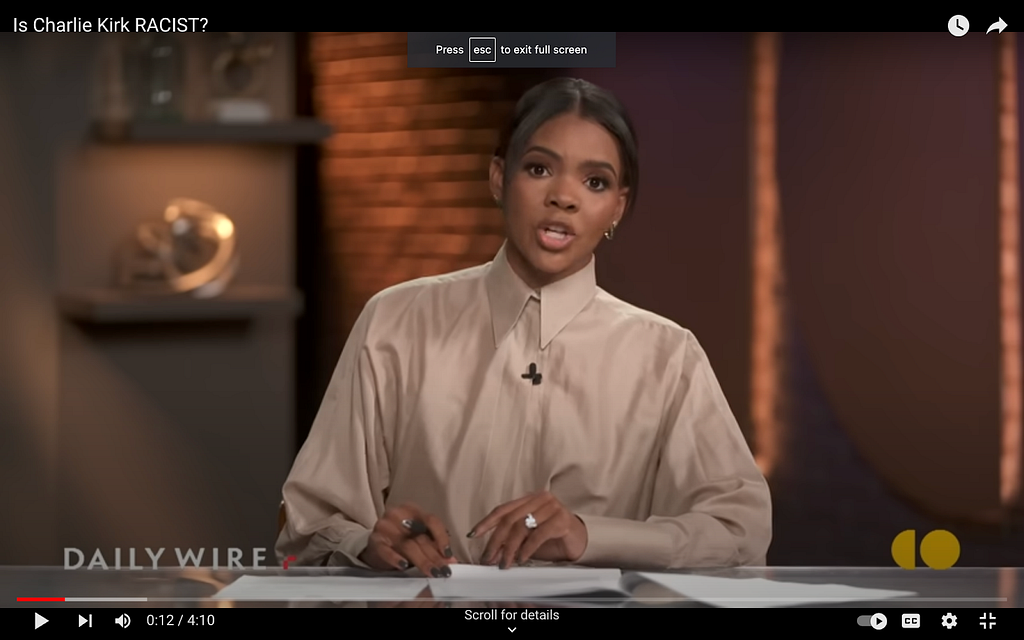 A screenshot from Candace Owens’s show on The Daily Wire. She wears a blouse in a muted tan colour with a very high, stiff, pointed collar.