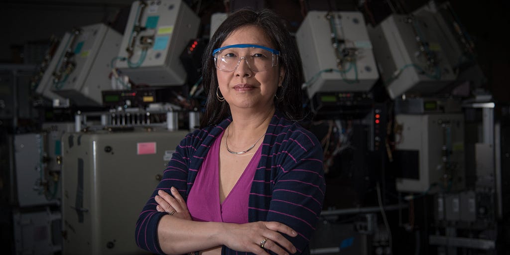 Joannie Chin poses in the lab wearing safety goggles, with her arms crossed.
