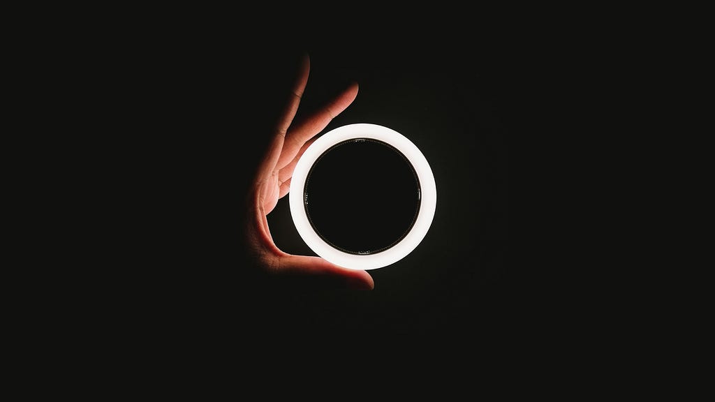 hand holding up a circle light against a black background