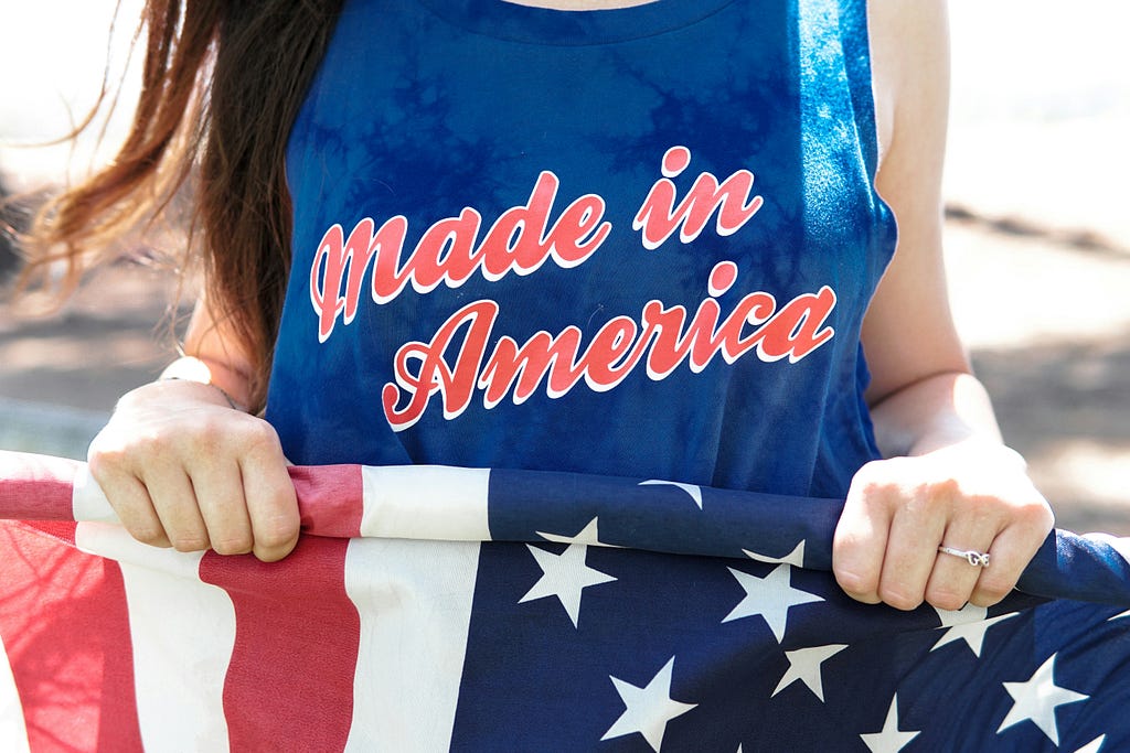 US flag held by somebody with “Made in America” on their T-shirt