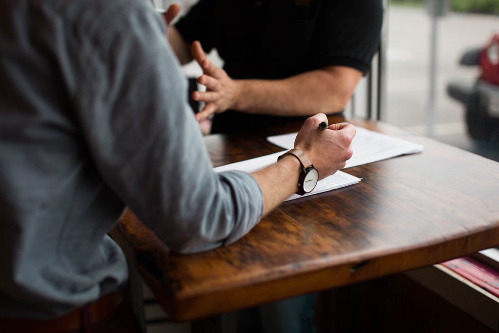 Two men standing at a table talking to each other