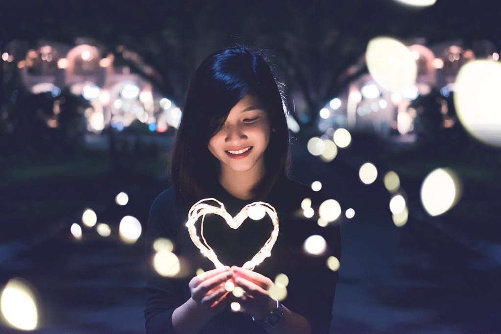 Asian woman holding illuminated heart